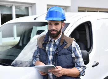 Man in hard hat standing outside a small white van